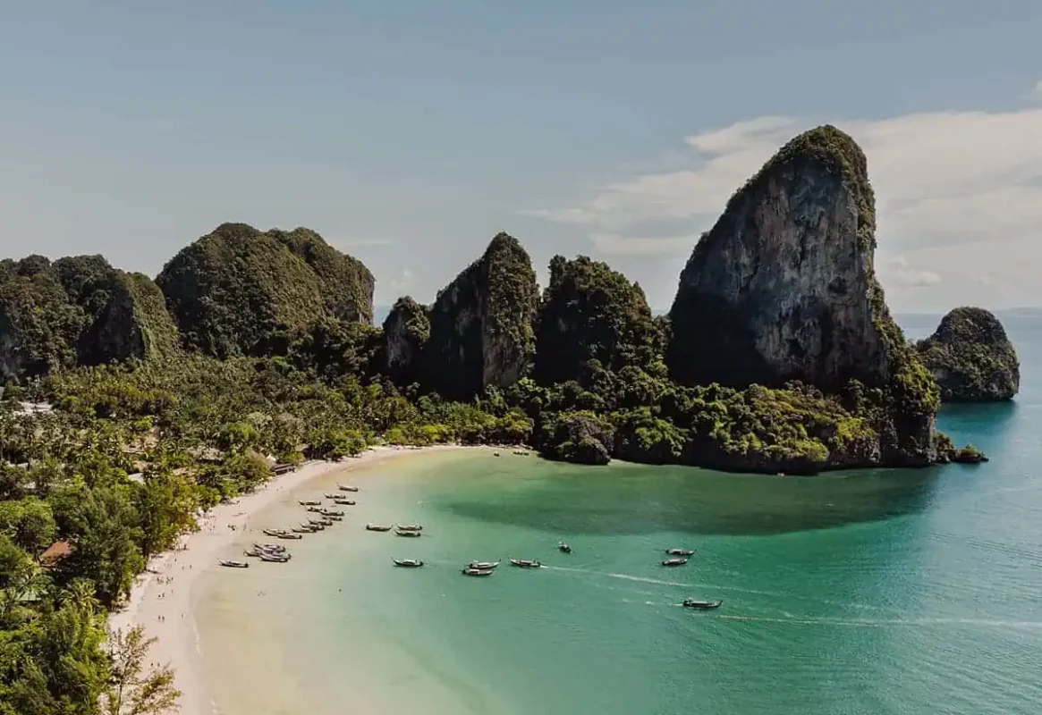 Ao Nang To Railay Beach: The ULTIMATE Guide 2025 9 Aerial view of Railay Beach with traditional longtail boats taking people from ao nang to railay beach, and limestone formations covered in jungle.