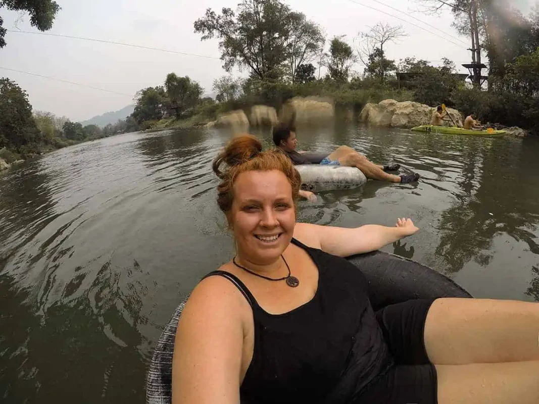 Tubing In Vang Vieng, Laos: ULTIMATE GUIDE 2025 15 Tasha Amy in a tube on a river with a blurry foreground, giving a relaxed vibe amidst the scenic hills of Vang Vieng tubing.