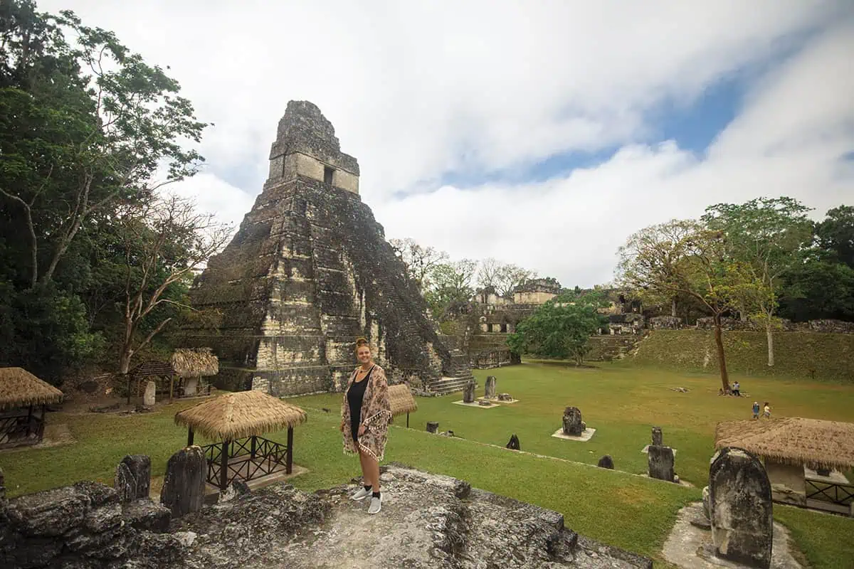 San Ignacio To Tikal & BEST Tikal Tours From San Ignacio 4 Tasha Amy gazing at the iconic Temple I at Tikal National Park, a popular destination for day trips from San Ignacio, with thatched-roof structures dotting the landscape.