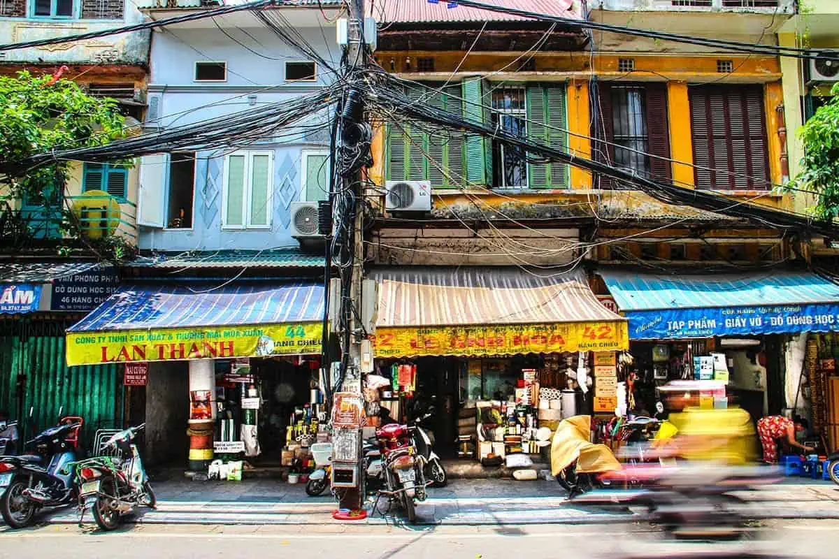 Scams In Vietnam: READ BEFORE YOU VISIT (2025) 11 A storefront in Vietnam with electrical wires above and signs in Vietnamese, selling appliances.