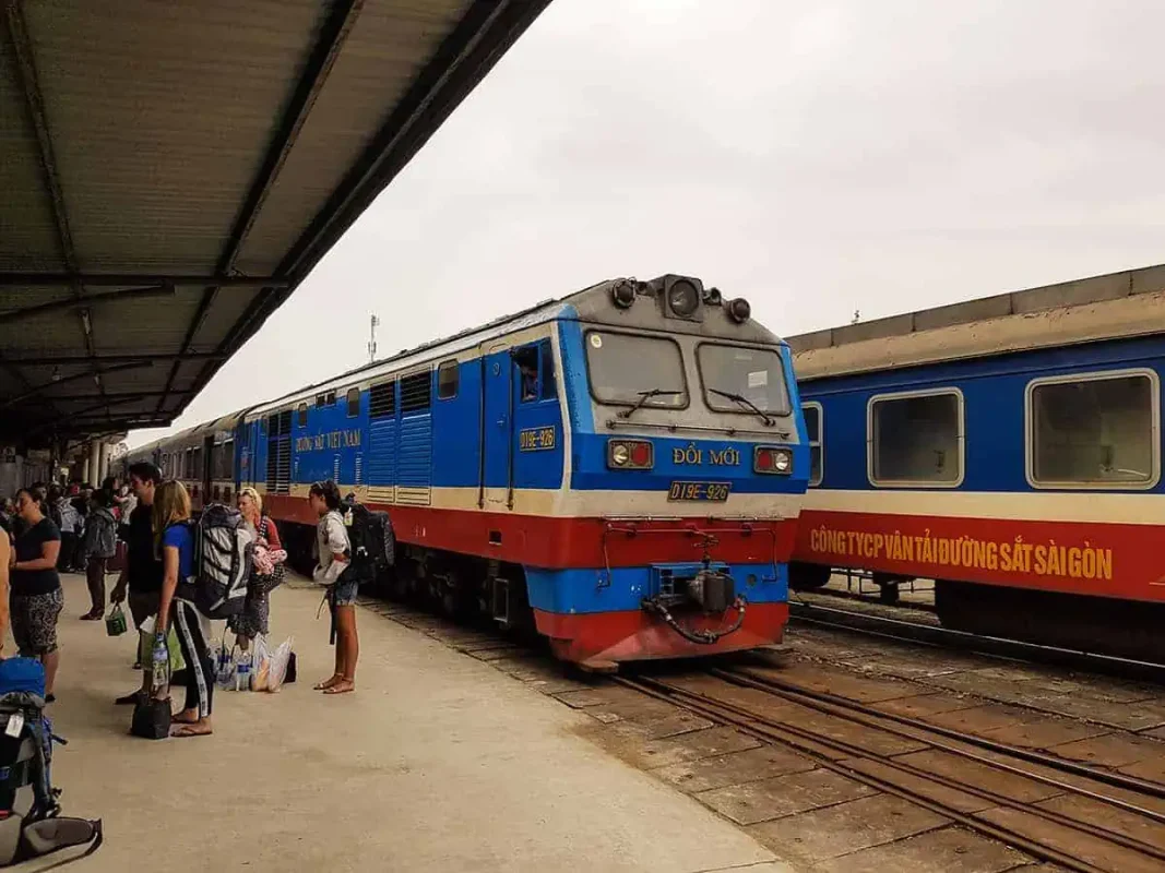 Vietnam Sleeper Train Ultimate Guide For Tourists (2025) 13 Passengers boarding a blue and red train at the station, preparing for an overnight journey through vietnam