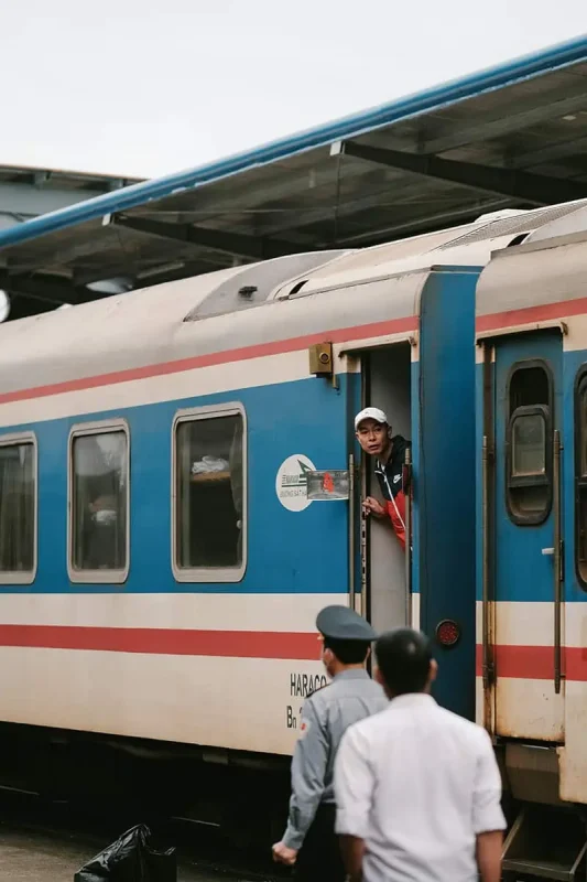 Vietnam Sleeper Train Ultimate Guide For Tourists (2025) 12 Train staff member looking out from the door of a sleeper train in Vietnam, ready to assist passengers.