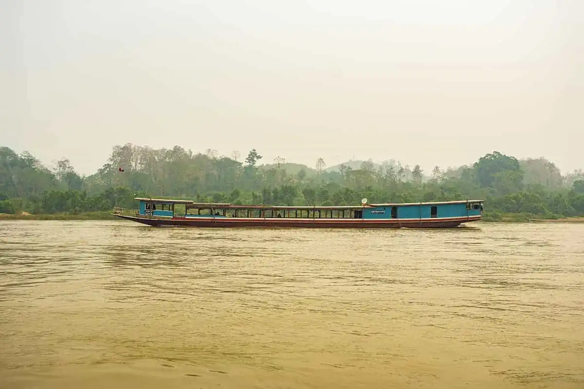 Taking The Slow Boat To Luang Prabang: BEST Tips 2025 12 Hazy atmosphere over the Mekong River with a slow boat in the distance