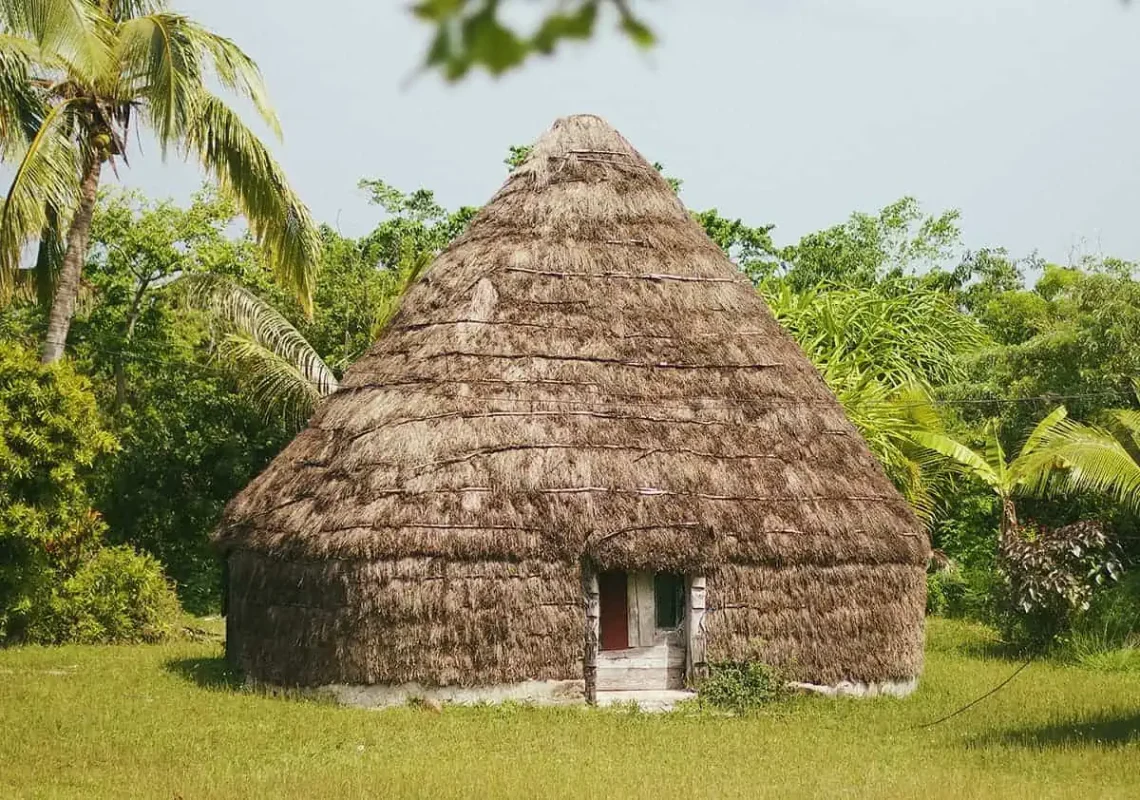 14 BEST Things To Do In Lifou: Cruise Passengers & More 11 A traditional thatched hut in Lifou, surrounded by lush greenery, presenting a slice of local culture and architecture in New Caledonia.