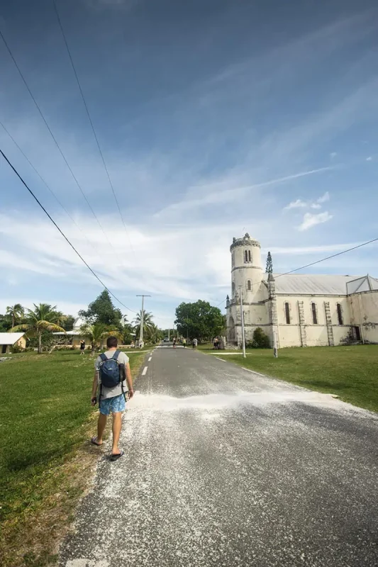 14 BEST Things To Do In Lifou: Cruise Passengers & More 23 A traveler walking towards a historical church on a sunny day in Lifou, an example of what to explore on the island when visiting from a cruise ship.