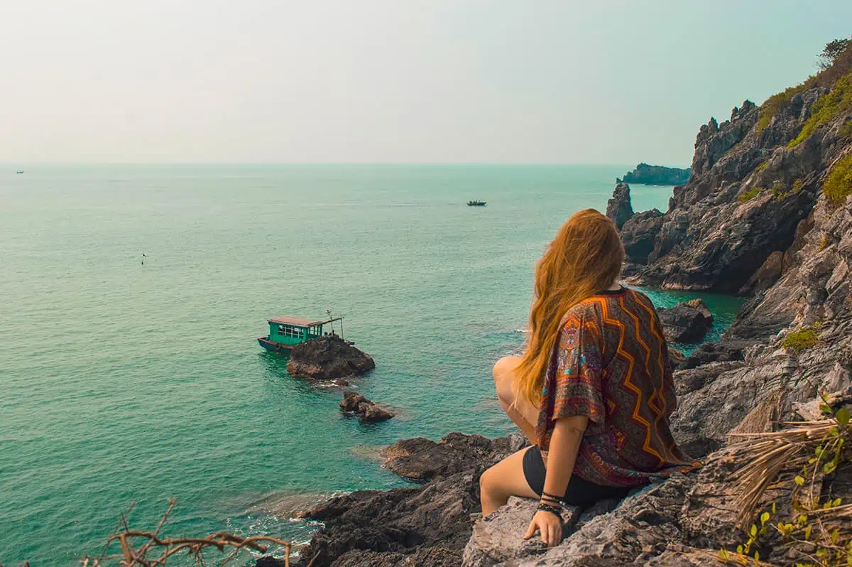 22+ Cheapest Countries To Backpack In The World! (2025) 12 A woman sitting on a cliff overlooking the ocean in ha long bay vietnam