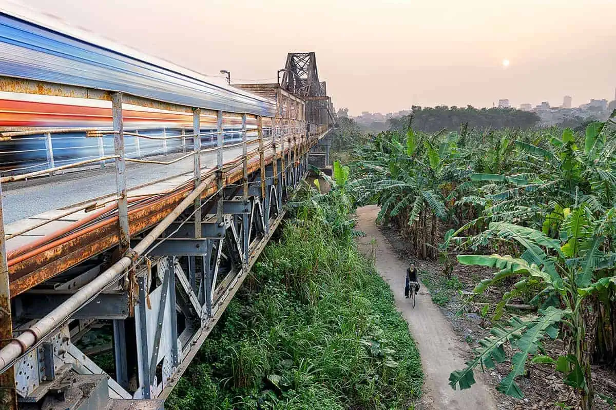 Vietnam Sleeper Train Ultimate Guide For Tourists (2025) 10 Long exposure capturing the motion of a Vietnam train on a bridge over lush greenery at sunset