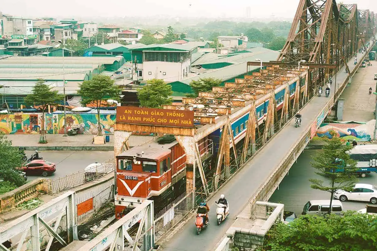 Vietnam Sleeper Train Ultimate Guide For Tourists (2025) 5 Elevated view of a first-class sleeper train in Vietnam traveling over a graffiti covered bridge