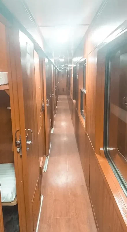 Hanoi To Sapa: Travel By Train, Bus, Or Taxi (2025) 7 The corridor of a Vietnam overnight train, showcasing the wooden interiors and private cabins
