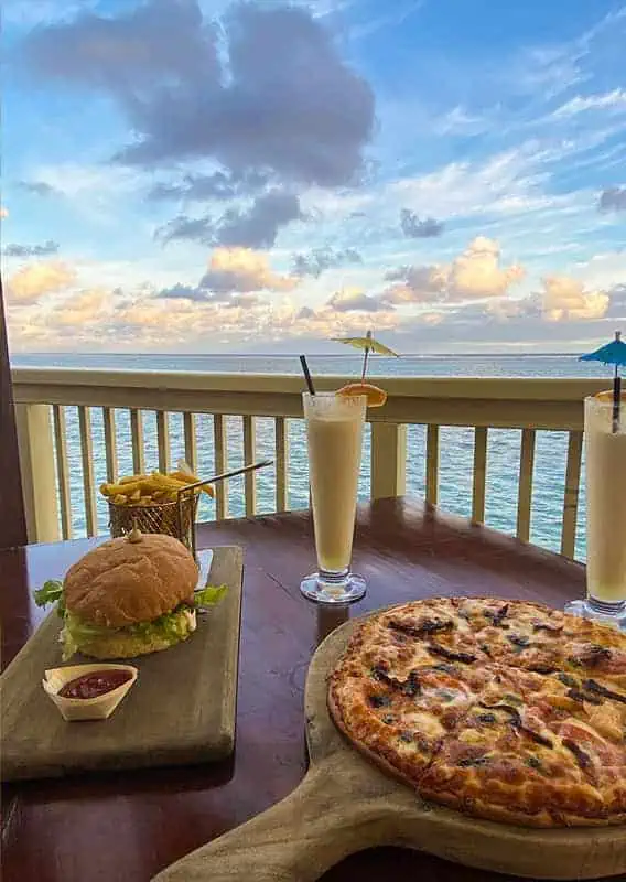 Where To Eat In Rarotonga: BEST Restaurants & Cafes 2025 28 Dining with a view in Rarotonga, featuring a juicy burger, refreshing pina colada, and a mouth-watering pizza, all set against a backdrop of the serene ocean at Captain Andy's Bar and Grill.